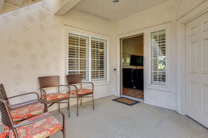 A room with two wicker chairs, a door, and a view into the kitchen. - Relax Poolside! Golfer's Paradise in Palm Desert (Palm Desert)