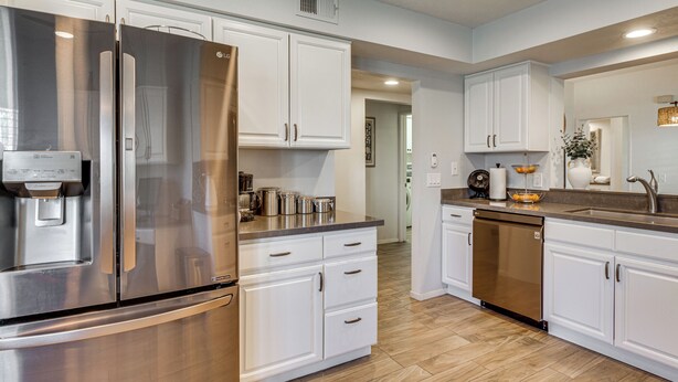 A modern kitchen with stainless steel appliances, white cabinetry, and a built-in dishwasher. - Relax Poolside! Golfer's Paradise in Palm Desert (Palm Desert)