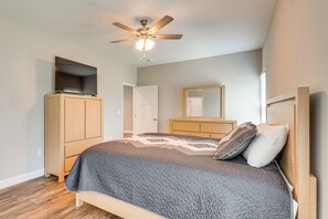 Un dormitorio con cama, ventilador de techo, armario, espejo y puerta.