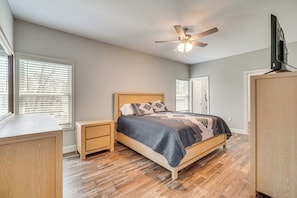 A bedroom with a bed, nightstands, a ceiling fan, and a TV on a stand.