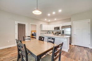 Una cocina moderna con armarios blancos, una mesa de comedor de madera y un microondas empotrado.