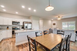 Una cocina moderna con armarios blancos, electrodomésticos de acero inoxidable y una mesa de comedor de madera.
