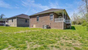 A two-story brick house with a balcony, a covered porch, and a small attached garage. - Walk to Cumberland County Playhouse! Modern Home (Crossville)