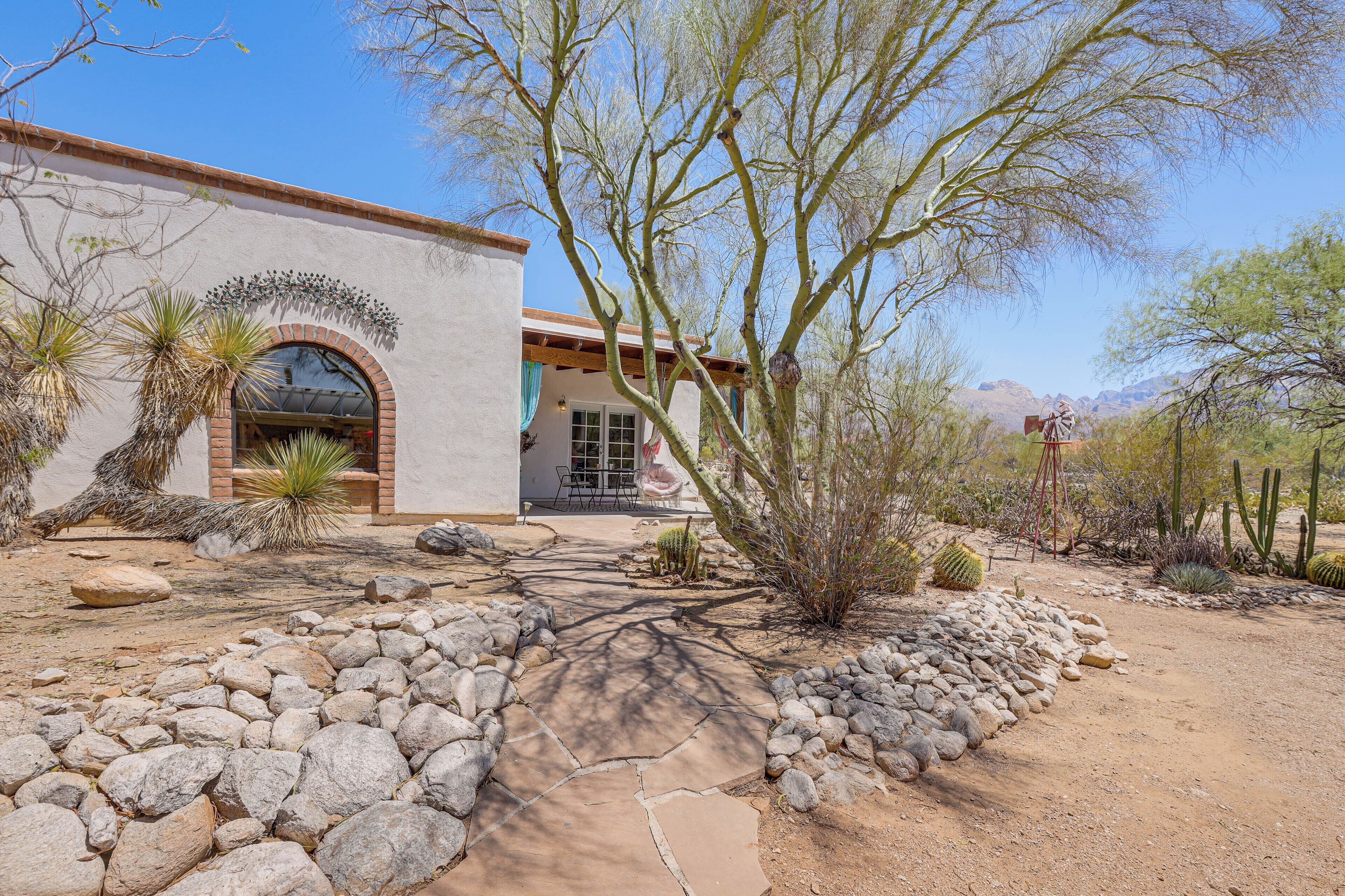 A desert-style building with a stone pathway leading to the entrance, surrounded by cacti and desert plants.