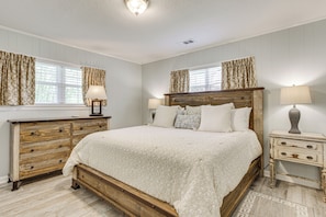 Un dormitorio con cama de madera, cómoda, mesita de noche y ventana con cortinas.