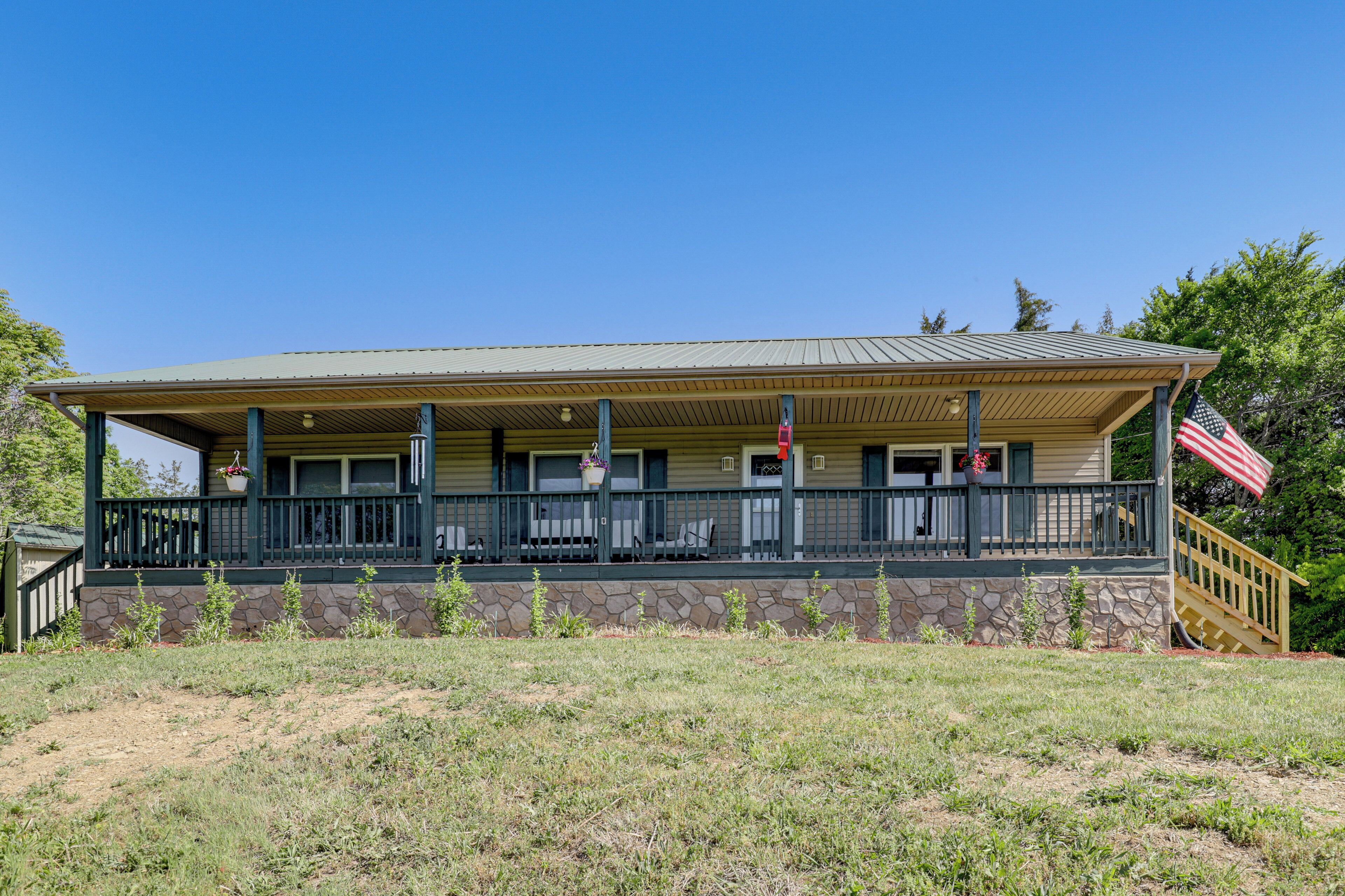 A two-story building with a porch, stone foundation, and a flag.