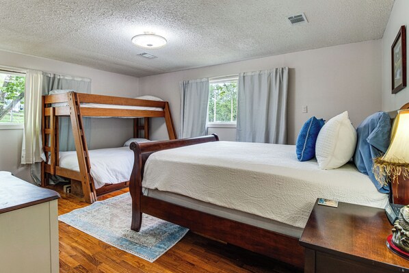 A bedroom with a bunk bed, a bedside table, a lamp, and a window with curtains. - Boating & Fishing Basecamp! Lake Norfork Views (Mountain Home)