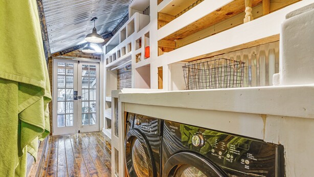 A laundry room with two front-loading washing machines, wooden flooring, and a high ceiling with exposed beams. - Walk to Granbury Square & Beach! 'texas Cottage' (Granbury)