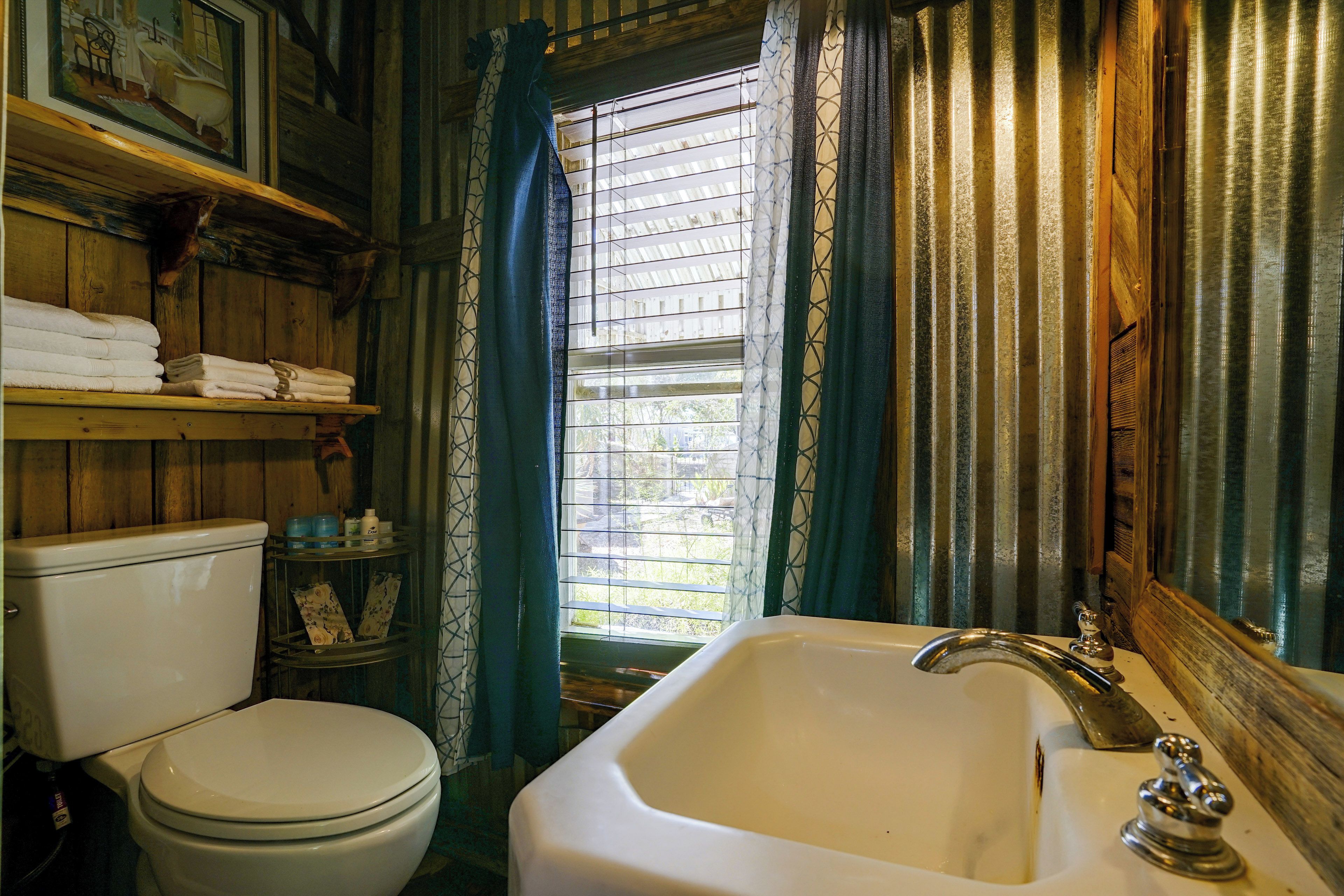 Ein Badezimmer mit Toilette, Waschbecken und einem Fenster mit Vorhängen.