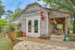 A rustic wooden building with a porch, stone pathway, and potted plants. - Walk to Granbury Square & Beach! 'texas Cottage' (Granbury)