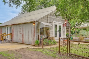A rustic building with a metal roof, a wooden staircase, and a fenced garden area.