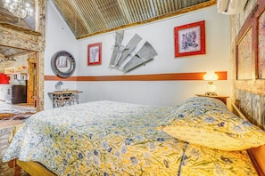 A bedroom with a bed, a wall-mounted mirror, and a framed artwork.