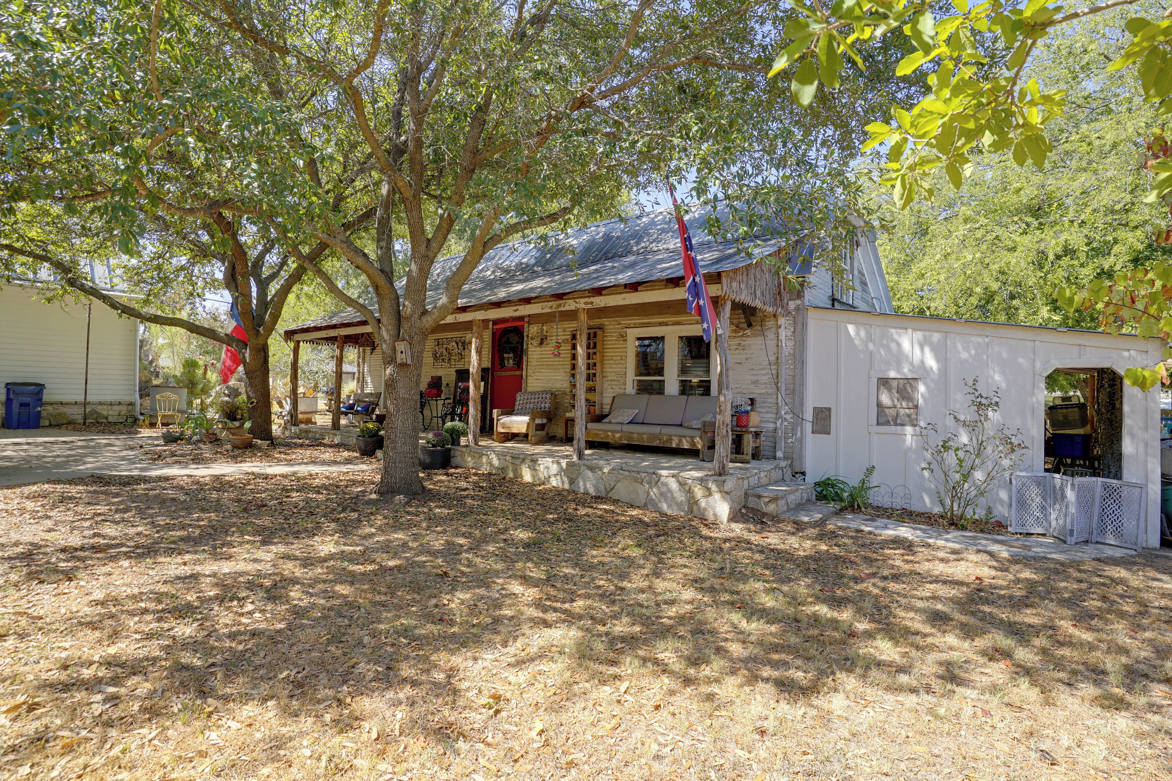 A rustic cabin with a porch, a small attached shed, and a flagpole.