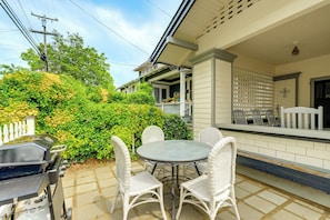 A patio with a round table and four chairs, a grill, and a white picket fence.