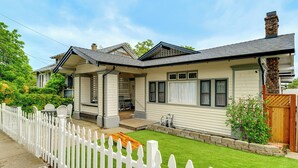 Een tweelaags huis met een witte hekken en een voortuin, met een keurig onderhouden gazon.