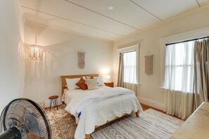 A bedroom with a bed, bedside tables, a standing fan, and a window with curtains. - Steps to Main St! Restored Sonora Bungalow w/ Yard (Sonora)