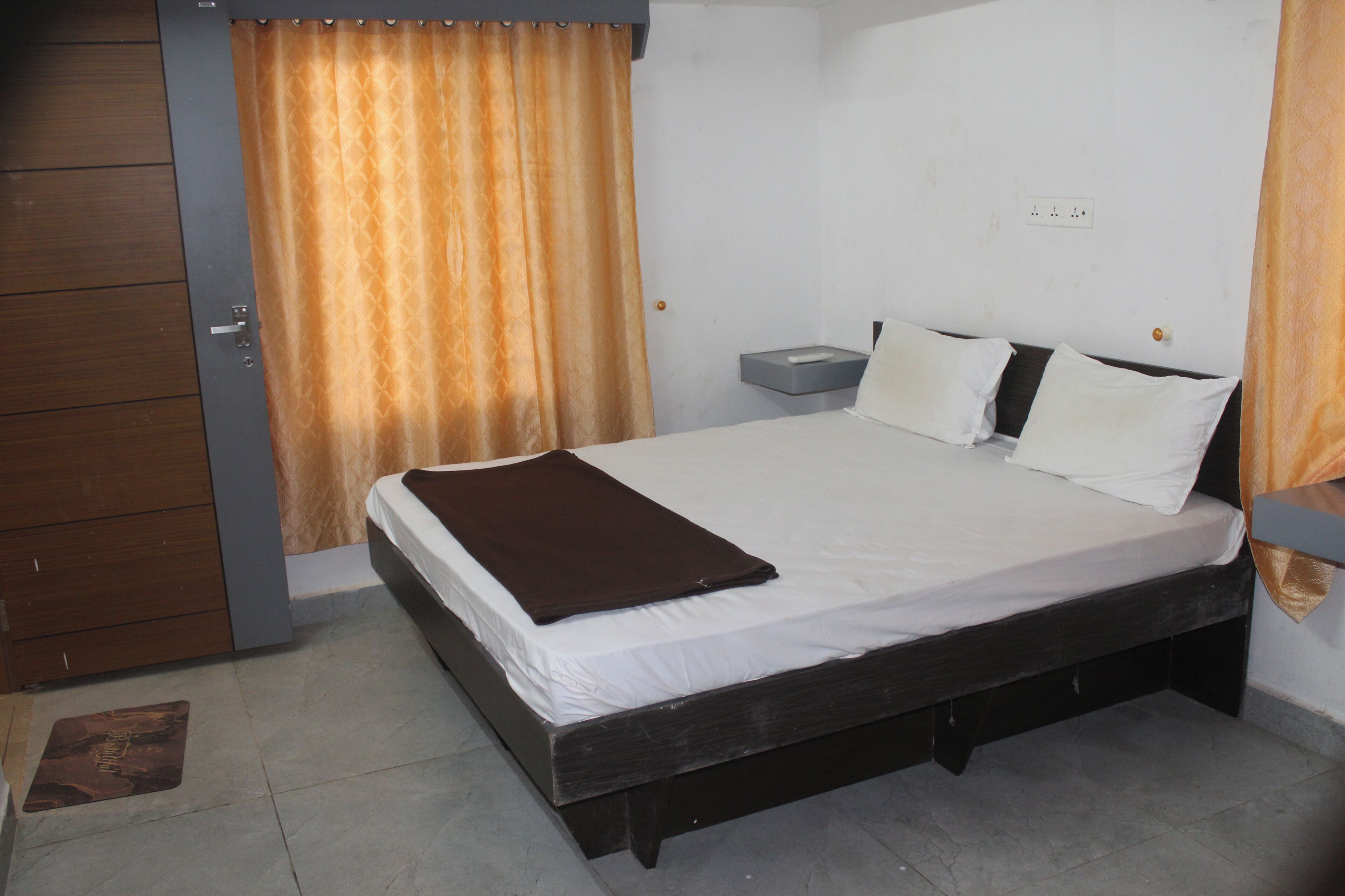 Une chambre à coucher comprenant un lit, une table de chevet, une commode et un rideau.