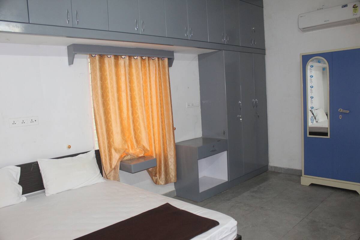 A bedroom with a bed, a wardrobe, a mirror, and a small shelf.