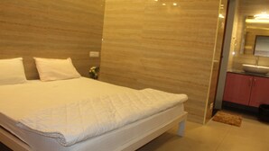Un dormitorio moderno con una cama grande, una mesita de noche pequeña y un baño con lavabo y espejo.