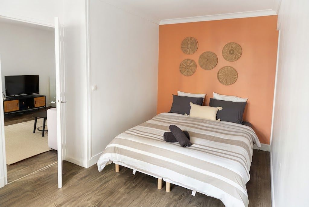 Een slaapkamer met een bed, kussens, een televisie en een bureau.
