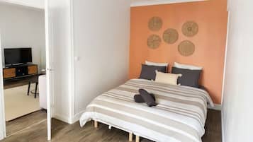 Un dormitorio con cama, almohadas, televisor y escritorio.