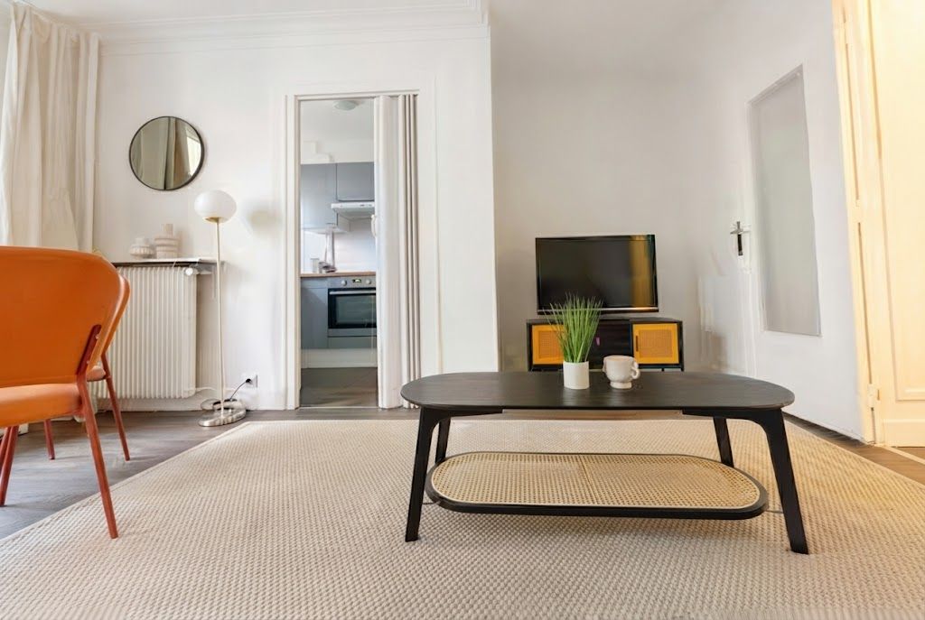 Een moderne woonkamer met een bank, een salontafel, een televisie en uitzicht op de keuken.