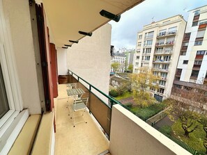 Ein Balkon mit Blick auf eine Wohngegend, einem Geländer und einem kleinen Tisch.