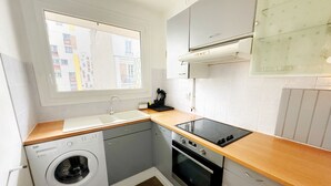 Cocina compacta con lavadora, horno y ventana que ofrece vistas al exterior.