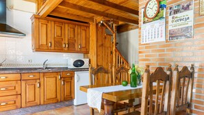 A kitchen with wooden cabinets, a microwave, a table with chairs, and a calendar on the wall. - Country House 'Casa de Aldea La Quintana' with Mountain Views (Las Viñas)
