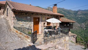 A stone building with a tiled roof, a wooden door, and a balcony with a white umbrella. - Country House 'Casa de Aldea La Quintana' with Mountain Views (Las Viñas)