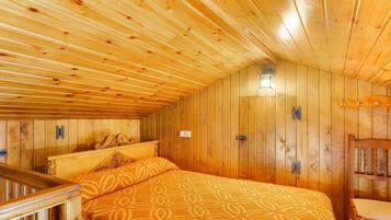 Um quarto de madeira com uma cama, uma cadeira e uma mesa pequena.