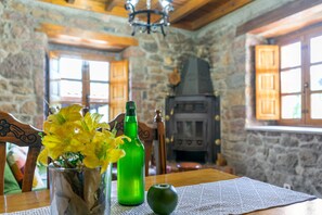 Ein rustikales Interieur mit einer Steinwand, Holzmöbeln, einem Kamin und einem Tisch mit einer Vase voller gelber Blumen.