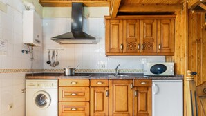 A kitchen with wooden cabinets, a built-in washing machine, a microwave, and a sink. - Country House 'Casa de Aldea La Quintana' with Mountain Views (Las Viñas)