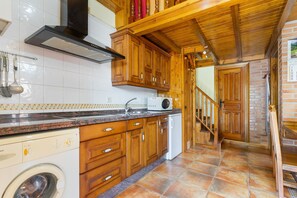 Une cuisine avec des meubles de rangement en bois, un four encastré et un lave-linge.