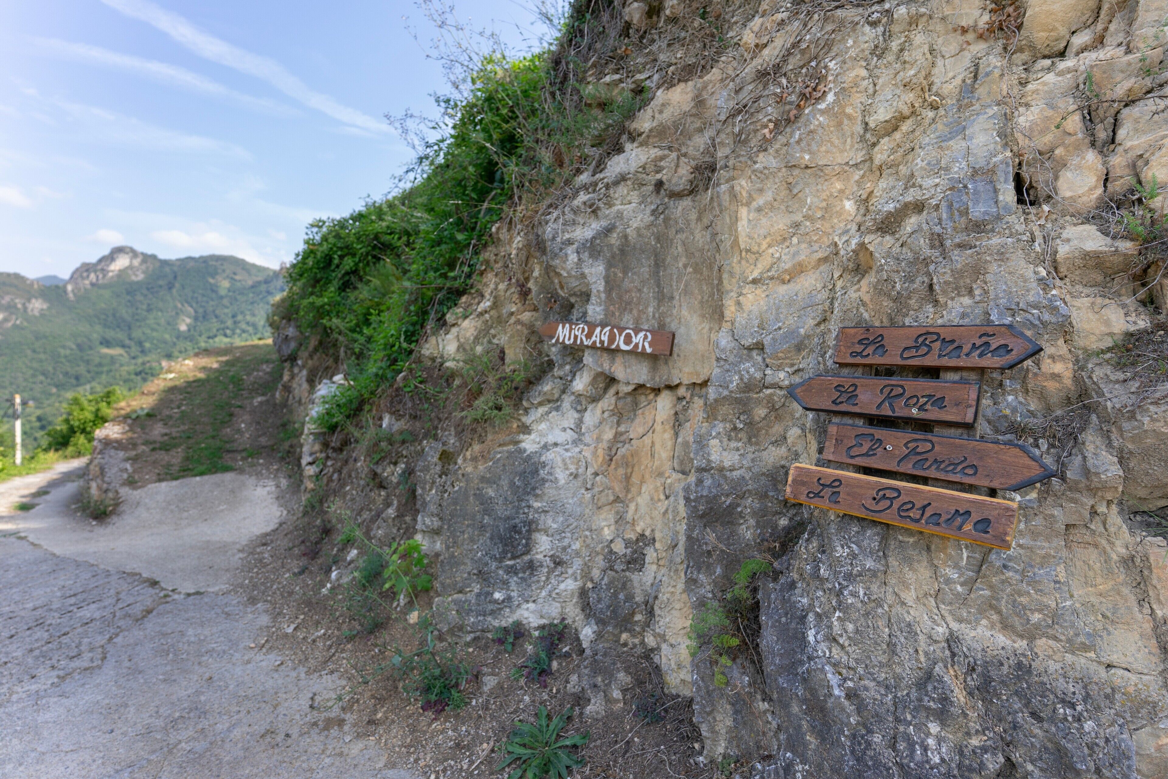 A rocky path with directional signs pointing to various destinations.