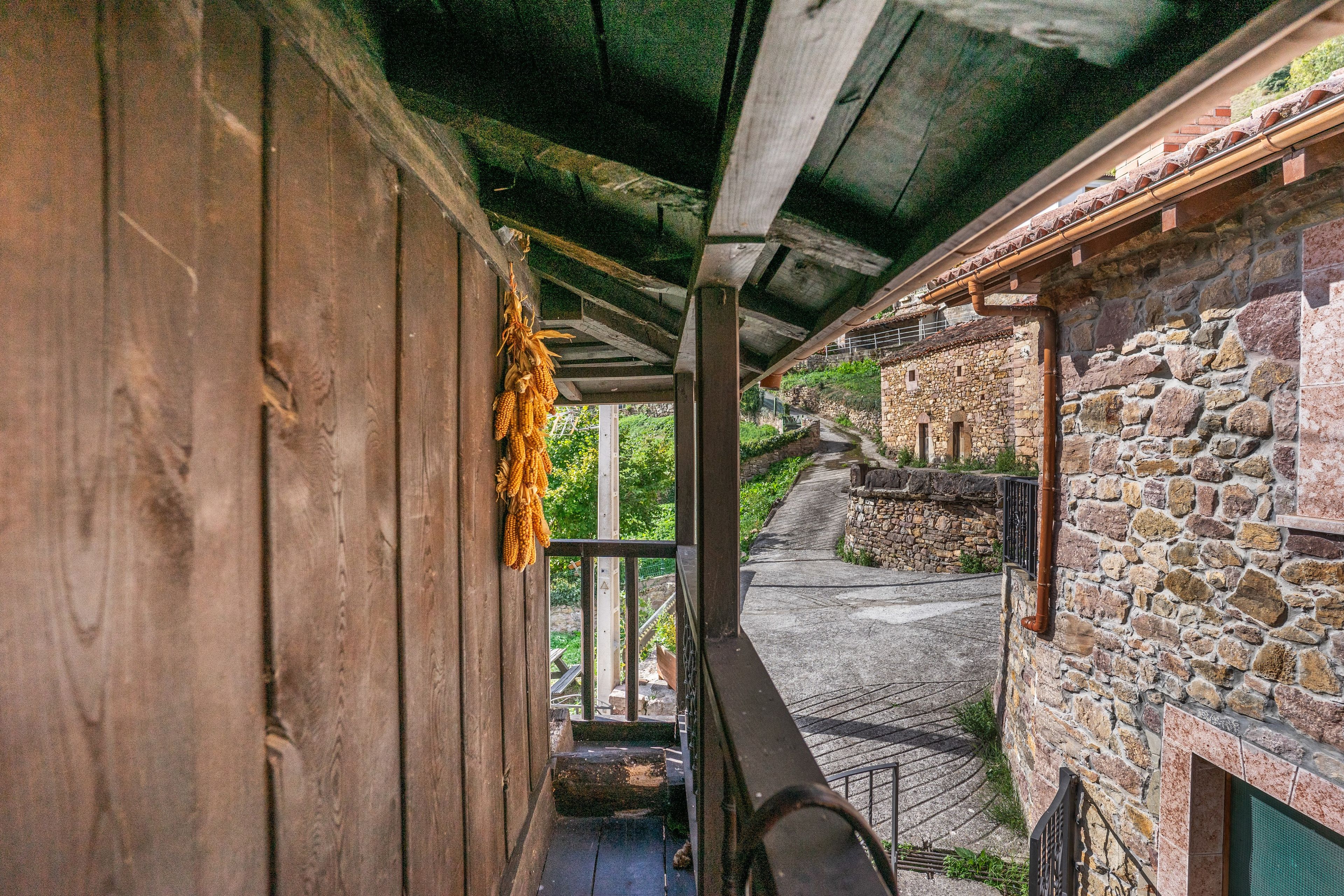 Un pasillo con una pared de madera a un lado y una pared de piedra al otro, que conduce a una escalera.