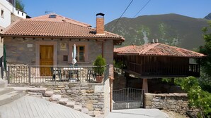 Un bâtiment en pierre avec un toit en tuiles, un balcon en bois et un escalier en pierre menant à l’entrée.