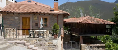 A stone building with a tiled roof, a wooden balcony, and a stone staircase leading to the entrance.
