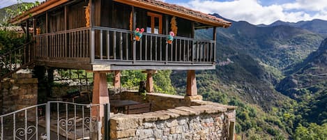 Una cabaña de madera con balcón con vistas a un paisaje montañoso.