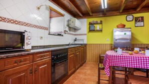 A kitchen with wooden cabinets, a stove, a microwave, and a refrigerator. - Casa de Aldea La Besana (Las Viñas)