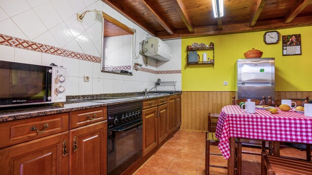 A kitchen with wooden cabinets, a stove, a microwave, and a refrigerator.