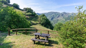 A picnic table with a bench, surrounded by a wooden fence, set against a backdrop of green hills and a clear sky. - Casa de Aldea La Besana (Las Viñas)