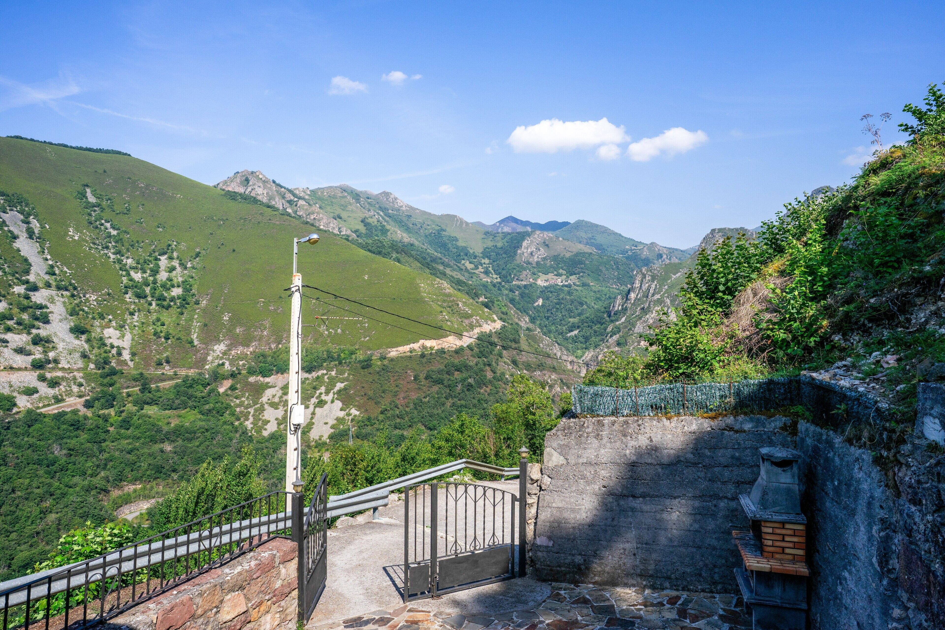 A stone staircase leading to a viewing platform with a metal railing, overlooking a mountainous landscape.