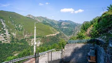A stone staircase leading to a viewing platform with a metal railing, overlooking a mountainous landscape.
