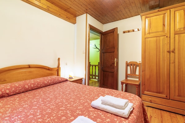 A bedroom with a wooden bed, a wooden wardrobe, and a green door leading to a balcony.