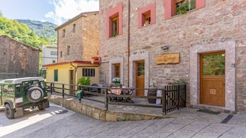 A stone building with a sign reading 'La Bodega' and a parked vehicle in front.
