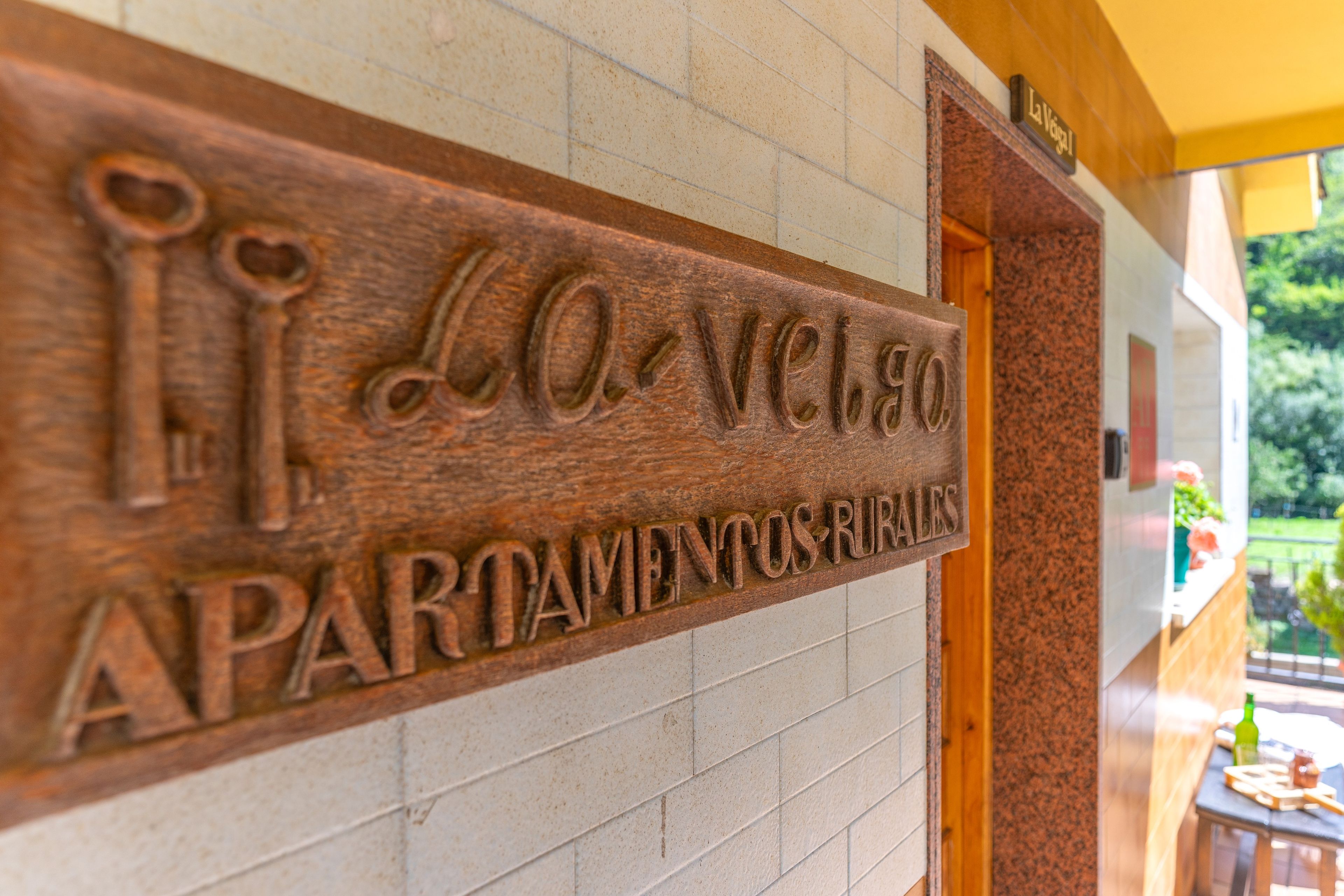 Un letrero de madera con el texto 'La Vecchia APARTMENTOS RURALES' y un símbolo de llave.