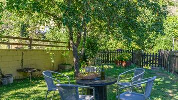 A patio with a round table and four chairs, surrounded by a yellow wall and a wooden fence.