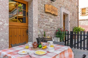 A breakfast table set outside a stone building with a wooden door and a sign reading 'La Bodega'.
