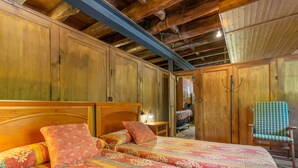 Una habitación con una cama de madera, una silla y una pared de ladrillo.